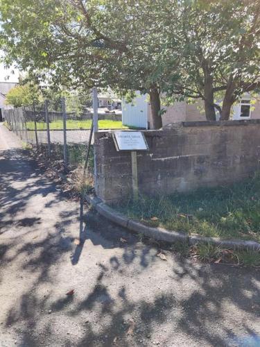 a fence with a sign next to a wall at Squirrels' Drey in Innerleithen