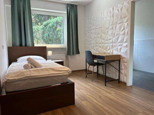 a bedroom with a bed and a desk and a window at Riverside Airport Hotel in Kelsterbach