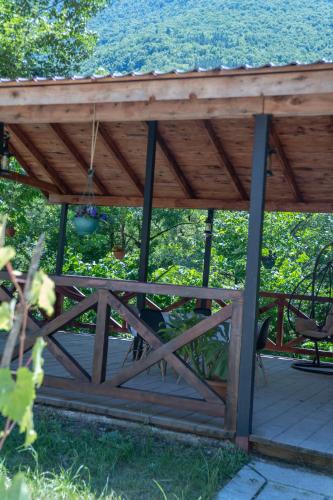 a wooden pergola with a table and chairs on a deck at Forest Side Gogolati in Ambrolauri
