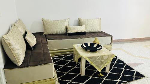 a living room with two beds and a table at KARAZ Homestay Grand appartement avec rooftop in Monte ʼArrouit