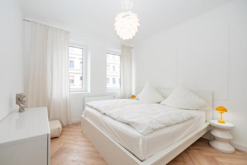 a white bedroom with a bed and a chandelier at Hanse Villa - Apartment Hamburg in Lübeck