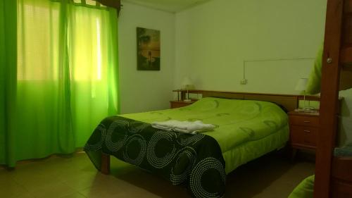 1 dormitorio con cama verde y cortina verde en Casa Huguito en Tinogasta