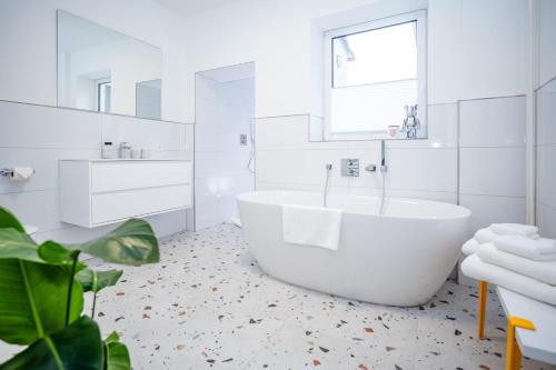 a white bathroom with a tub and a window at Hanse Villa - Apartment Hamburg in Lübeck