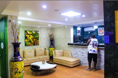 un hombre está de pie en una sala de estar en St. Regis Hotel & Resort - Benin City, en Benin City