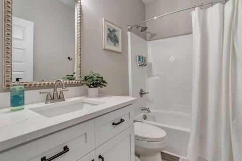 une salle de bain blanche avec un lavabo et des toilettes dans l'établissement Waveland Beach Cottage 215, à Waveland
