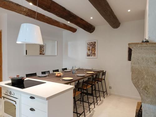 une cuisine avec une longue table avec des tabourets dans l'établissement Maison de Village 18ème Siècle Familiale 3 Chambres, à Mus