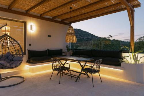 a patio with a table and chairs and a couch at Villa Aldea - Luxury Boho Style in Melidhónion