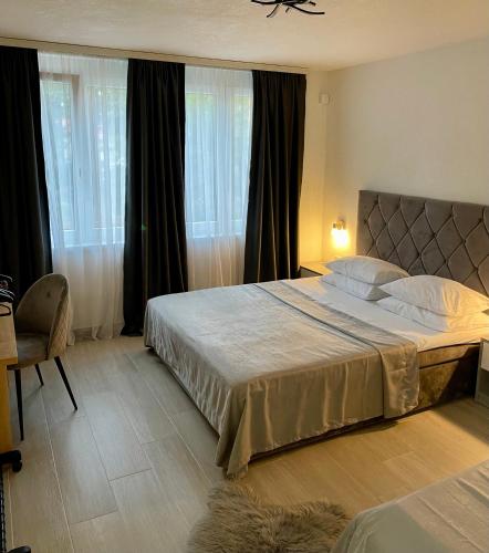 a bedroom with a large bed and windows at ANET Apartman Visoko in Visoko