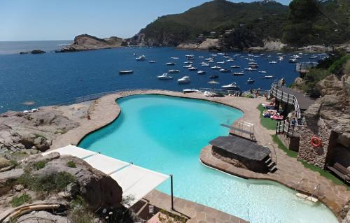 a large swimming pool next to a body of water at Cap Sa Sal - Apartamento Vistamar in Begur