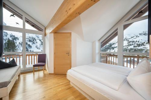 - une chambre avec un lit et de grandes fenêtres dans l'établissement Appartement Haus Faßwald, à Obertauern