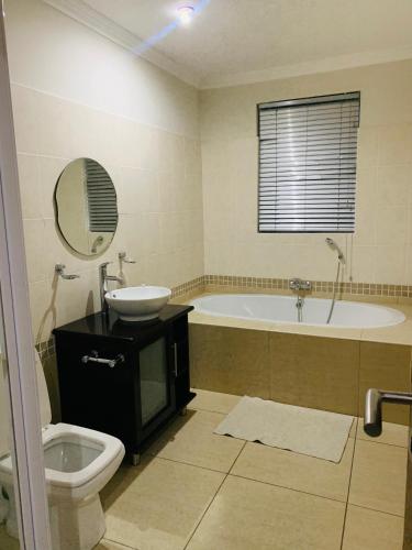 ein Badezimmer mit einer Badewanne, einem Waschbecken und einem WC in der Unterkunft Atonement private room in Matsapha