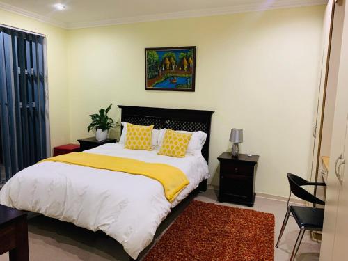 ein Schlafzimmer mit einem Bett mit gelben und weißen Kissen in der Unterkunft Atonement private room in Matsapha