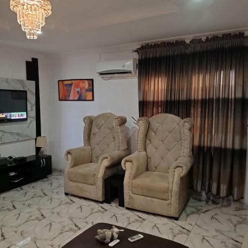 ein Wohnzimmer mit 2 Stühlen und einem TV in der Unterkunft J Lounge in Ikorodu