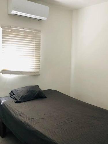 a bedroom with a bed and a window with a pillow at Bonito y cómodo departamento 2R in Mexicali