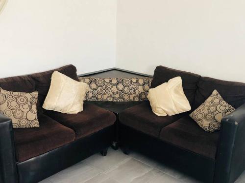 two brown leather couches with pillows on them at Bonito y cómodo departamento 2R in Mexicali