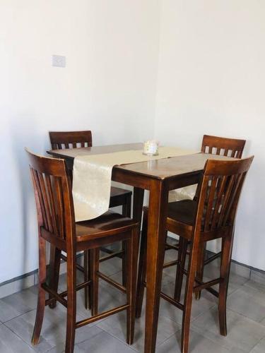 une table en bois avec quatre chaises et un tissu de table blanc dans l'établissement Bonito y cómodo departamento 2R, à Mexicali