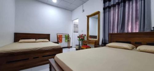 a bedroom with two beds and a mirror at Nilaveli Guest House in Nilaveli