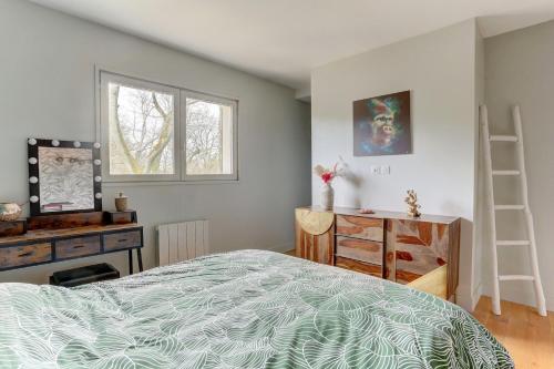 Schlafzimmer mit einem Bett, einem Schreibtisch und einem Fenster in der Unterkunft Le Merisier - Guyancourt in Guyancourt