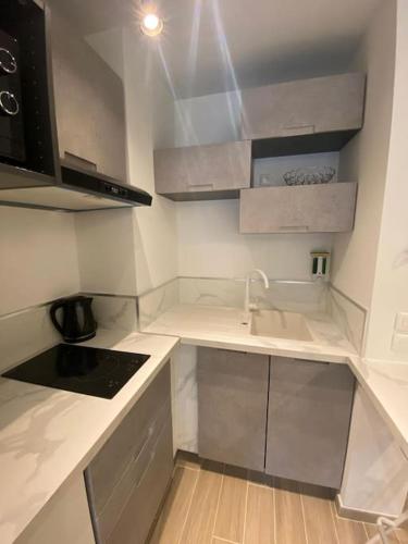 une petite cuisine avec des comptoirs blancs et un évier dans l'établissement Appartement neuf Pointe Croisette, 50 m de la mer, à Cannes