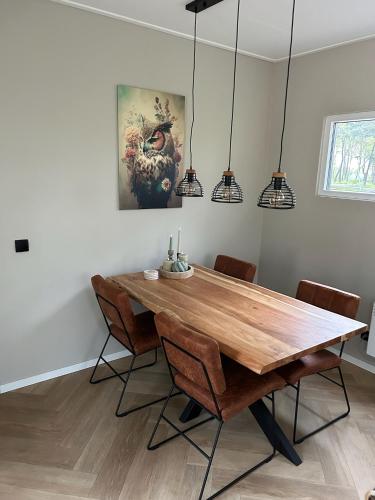 a dining room with a wooden table and chairs at Bos chalet Hellendoorn met Hottub in Haarle