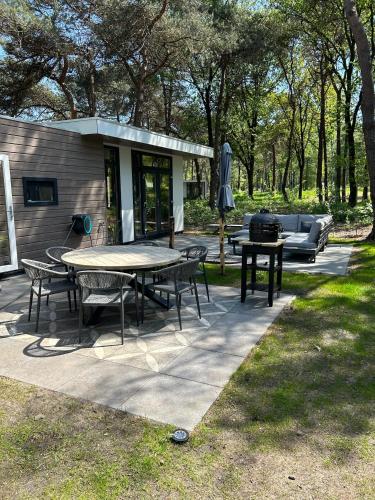 a patio with a table and chairs and a couch at Bos chalet Hellendoorn met Hottub in Haarle