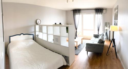 une chambre blanche avec un lit et une chaise dans l'établissement Appartement 35m² terrasse sud, à Caen