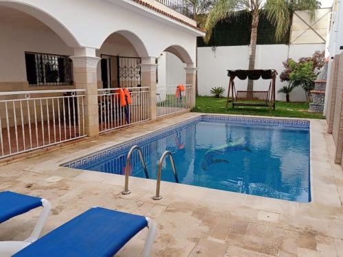basen z niebieskimi krzesłami obok domu w obiekcie Magnifique villa avec piscine 