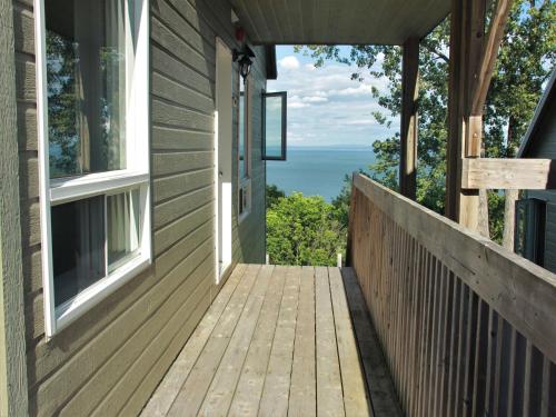 a wooden porch with a view of the ocean at Studios d'hébergement du Domaine in Saint-Irénée