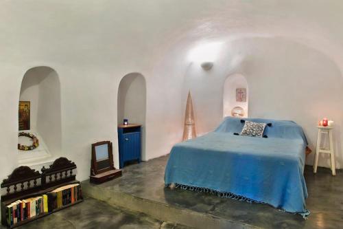 a bedroom with a blue bed in a white room at PORI HOUSE-VOLCANO VIEW in Oia
