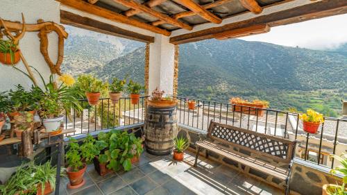 a balcony with a bench and potted plants at Hotel La Fragua II in Trevélez