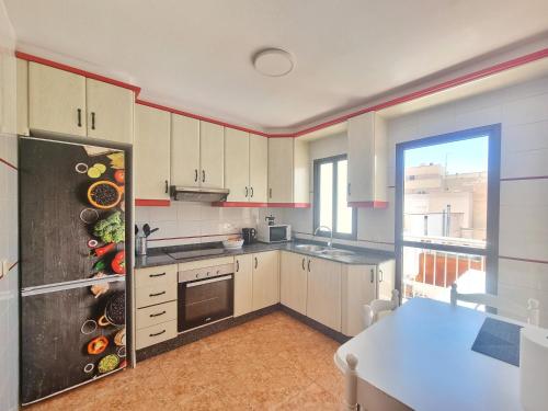 a kitchen with white cabinets and a large window at Céntrico, con terraza y barbacoa - by Aloha Palma in Águilas