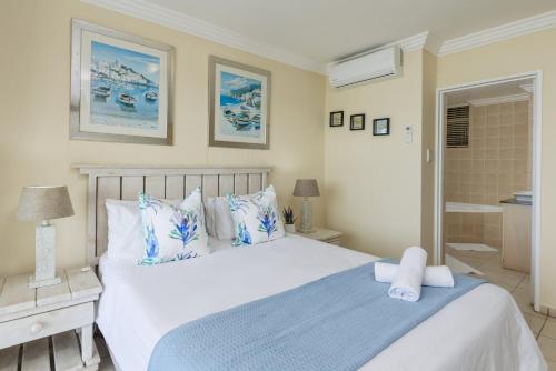 a bedroom with a large white bed and a bathroom at Santorini 401A in Margate