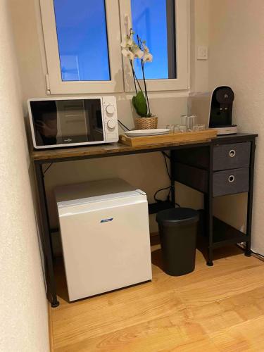 un four à micro-ondes posé sur un bureau avec un réfrigérateur dans l'établissement Chambre proche de la citadelle, à Montmédy