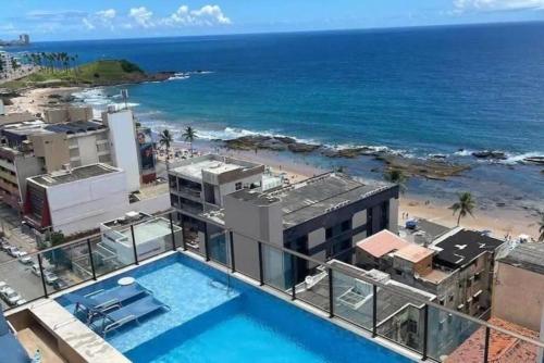 a view of the ocean from a building with a swimming pool at Barra, compacto, novo e aconchegante in Salvador