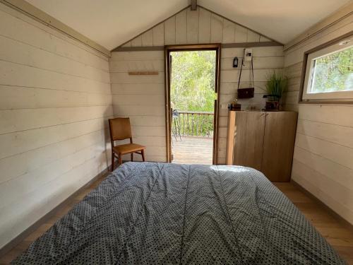 ein Schlafzimmer mit einem Bett in einem Zimmer mit einem Fenster in der Unterkunft Petit chalet en pleine nature avec accès rivière in Venaco