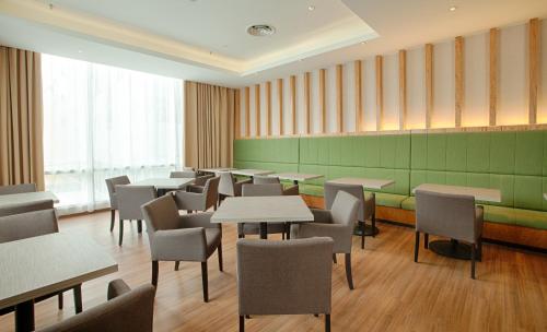 a restaurant with tables and chairs and a green wall at WP Hotel in Kuala Lumpur