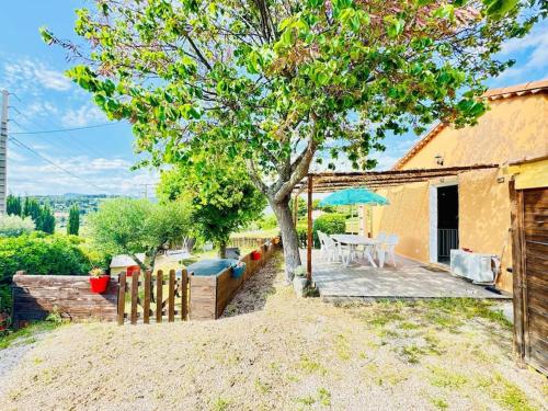 a patio with a tree and a table with an umbrella at Maison climatisée avec piscine proche bandol in Le Beausset
