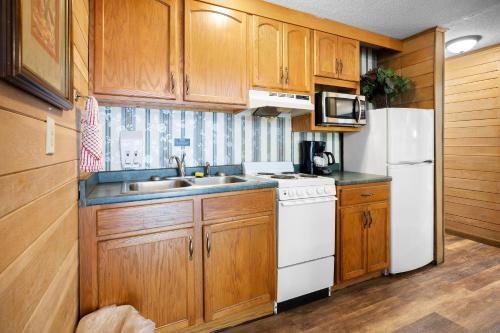 a kitchen with wooden cabinets and a white refrigerator at Carr's Northside Hotel and Cottages in Gatlinburg