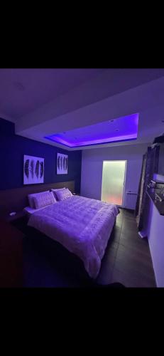 - une chambre avec un grand lit et un éclairage violet dans l'établissement Villa Bass, à Bab el Oued