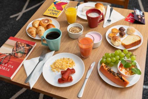 a wooden table with plates of breakfast food on it at ibis Sao Paulo Paulista in Sao Paulo
