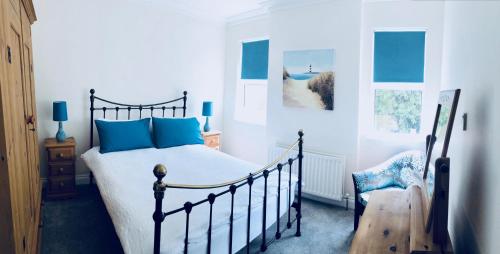 a bedroom with a bed with blue pillows and a chair at Oscar's by the Sea in Bangor