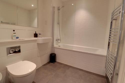 a white bathroom with a toilet and a shower at Van Gogh Apartment, Bedford - Fast Wifi, Gym & FREE Parking in Bedford