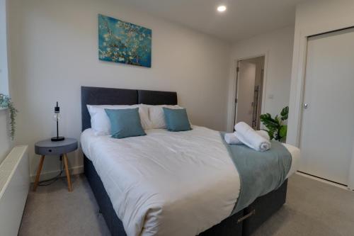 a bedroom with a large bed with blue pillows at Van Gogh Apartment, Bedford - Fast Wifi, Gym & FREE Parking in Bedford