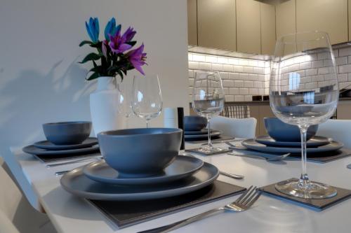 a table with plates and wine glasses on it at Van Gogh Apartment, Bedford - Fast Wifi, Gym & FREE Parking in Bedford