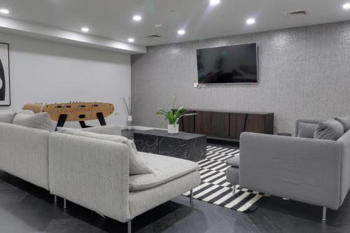 a living room with couches and a tv on a wall at Van Gogh Apartment, Bedford - Fast Wifi, Gym & FREE Parking in Bedford