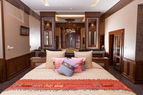een slaapkamer met een groot bed met kussens bij Ammatara Pura Pool Villa in Lamai