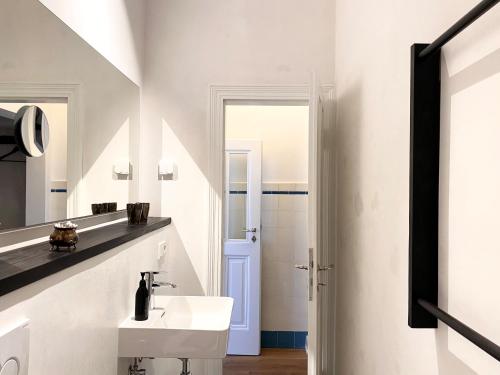 ein weißes Badezimmer mit Waschbecken und Spiegel in der Unterkunft Zehuus Beletage in Köln