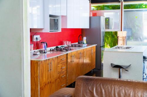 eine Küche mit Holzschränken und einer roten Wand in der Unterkunft Inkanyezi Guest house in Durban