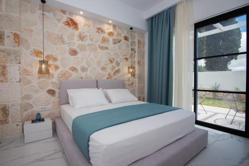 - une chambre avec un grand lit blanc et un mur en pierre dans l'établissement LUZ BLANCA, à Agios Leon
