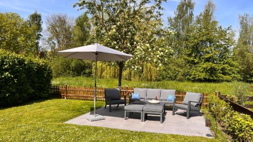 eine Terrasse mit einem Tisch, Stühlen und einem Sonnenschirm in der Unterkunft Haus Sansibar auf Poel mit Sauna& Kamin, ruhiger Garten-700m vom Strand! in Insel Poel